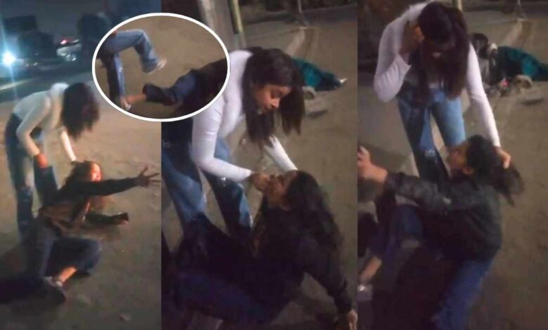 रात के समय सड़क पर एक लड़की दूसरी लड़की के बाल पकड़कर मारती हुई।